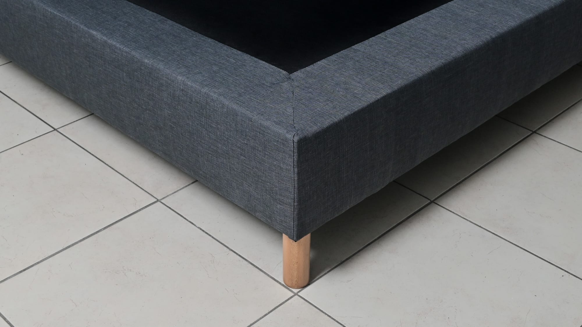 Détail du tissu gris anthracite et des pieds en bois du sommier